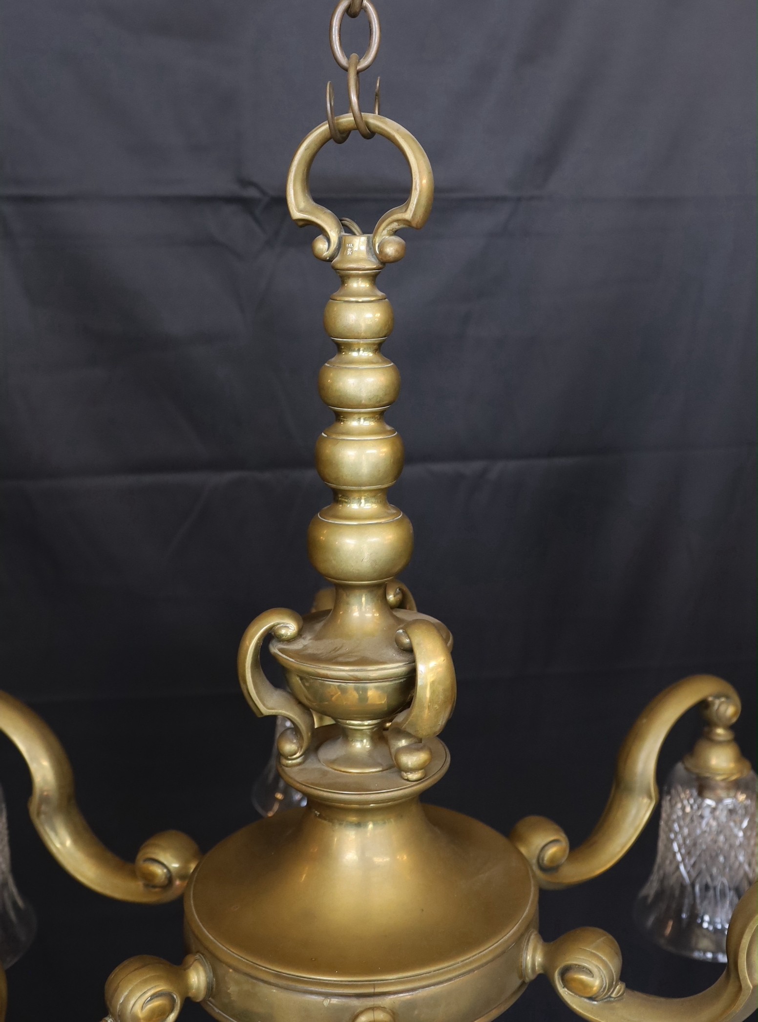 An early 20th century English bronze six light chandelier with cut glass shades, drop 70cm. width 80cm